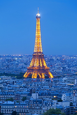 Illuminated Eiffel Tower, viewed over rooftops, Paris, France, Europe