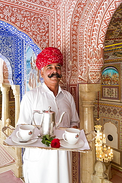 Waiter carrying tea tray in ornate passageway, Samode Palace, Jaipur, Rajasthan, India, Asia