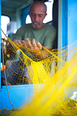 Fisherman cleaning his nets, Mykonos, Greek Islands, Greece, Europe 