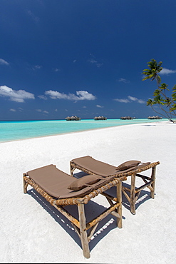 Lounge chairs and tropical beach, water villas and palm trees, Maldives, Indian Ocean, Asia