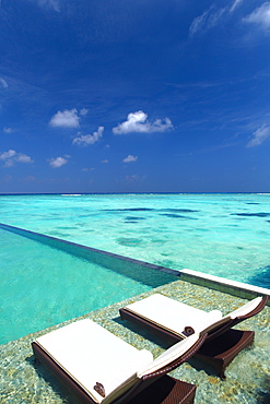 Lounge chairs on infinity pool and tropical beach, The Maldives, Indian Ocean, Asia