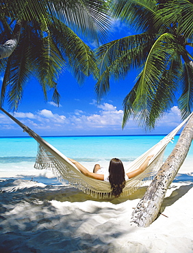 Woman sitting in hammock on beach, Maldives, Indian Ocean, Asia