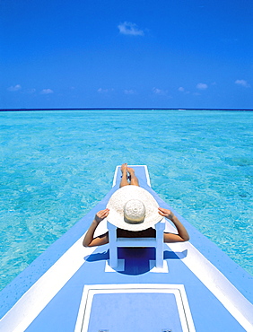 Woman relaxing on deck of boat, Maldives, Indian Ocean, Asia