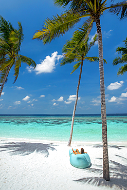 woman relaxing in a Bean Bag Chair overrloking the sea, palmtress , maldives