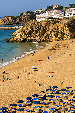 Cliffside, beachgoers and umbrellas at Praia dos Pescadores or Fishermans Beach, Albufeira, faro district, algarve, portugal, europe.