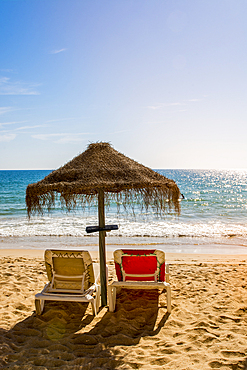 Inviting beach umbrella below the Red sandstone cliffs of Praia da Falésia, Albufeira district, souther, portugal