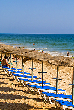 Beachgoers at Red sandstone cliffs of Praia da Falésia, Albufeira district, souther, portugal