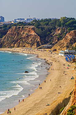 Beachgoers at Red sandstone cliffs of Praia da Falésia, Albufeira district, souther, portugal