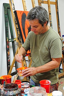 Mexico, Bajio, San Miguel de Allende, Artist Juan Ezcurdia in his studio mixing paint.