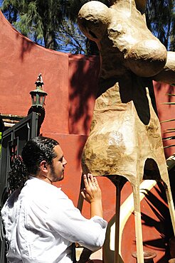 Mexico, Bajio, San Miguel de Allende, Artist Alejandro Lopez with sculpture at his studio.