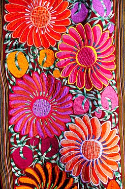 Mexico, Bajio, San Miguel de Allende, Detail of brightly coloured embroidered textile in arts shop with flower design in pink red and orange.