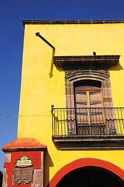 Mexico, Bajio, San Miguel de Allende, El Jardin Part view of yellow painted exterior facade of building with French windows and balcony.