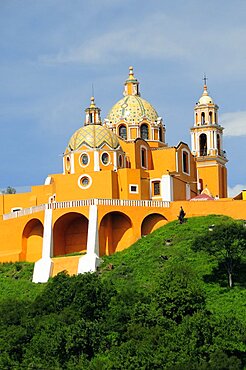 Mexico, Puebla, Cholula, Church of Neustra Senor de los Remedios or Our Lady of Remedios on wooded hillside above the pyramid ruins with brightly painted exterior in neoclassical style.