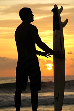 Mexico, Oaxaca, Puerto Escondido, Surfer and board silhouetted at sunset on Playa Zicatela.