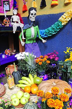 Mexico, Michoacan, Patzcuaro, Dia de los Muertos Day of the Dead altar with skeleton figures food and drink and colourful paper decorations.