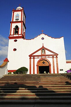 Mexico, Veracruz, Papantla, Cathedral de la Asuncion white and red painted exterior facade and bell tower with flight of steps to entrance.