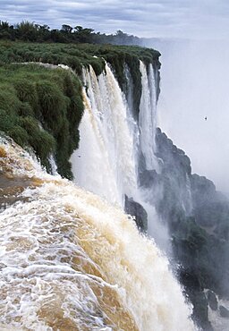 ARGENTINA Misiones Province Iguazu National Park Iguazu Falls cascading over green cliffs.