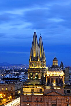 Mexico, Jalisco, Guadalajara, Cathedral domed roof and bell towers at night with city spread out behind.