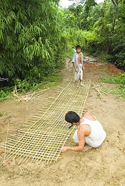 Bangladesh, Chittagong Division, Khagrachari, Two men weaving a large bamboo fence panel.