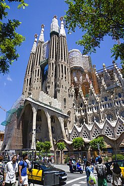 Spain, Catalonia, Barcelona, Tourists viewing the basilica church of Sagrada Familia deisigned by Antoni Gaudi in the Eixample district.