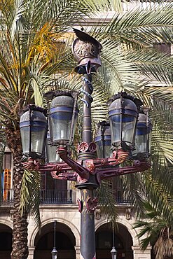 Spain, Catalonia, Barcelona, Ornate street lamp and palm trees in Placa Reial.