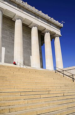 USA, Washington DC, National Mall, Lincoln Memorial, A tourist sitting among the Doric columns of the peristyle surrounding the memorial.