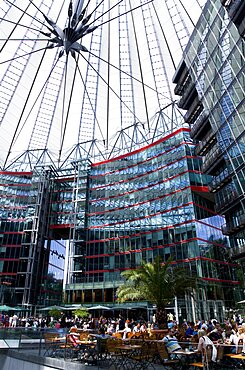 Germany, Berlin, Mitte, Potsdamer Platz, The Sony Centre designed by architect Helmut Jahn with the canopy over the central Forum of restaurants, offices, cinemas, shops and apartments with people eating at tables.