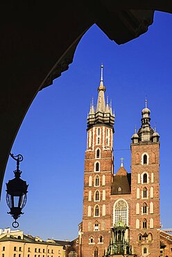 Poland, Krakow, Rynek Glowny or Main Market Square, St Mary's Church also known as St Marys Basilica, view through an arch of the Cloth Hall.