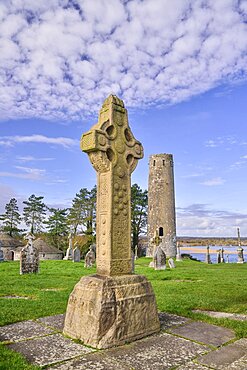 Ireland, County Offaly, Clonmacnoise Monastic Settlement, South Cross and Round Tower with River Shannon in the background.