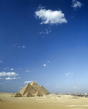 EGYPT Cairo Area Giza Pyramids in desert landscape with shadows cast over sand and Cairo beyond.