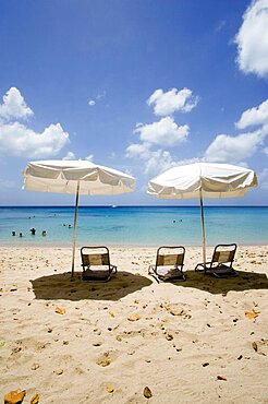 WEST INDIES Barbados St Peter Sun shade umbrellas and chairs on Gibbes Beach with people swimming in the calm sea