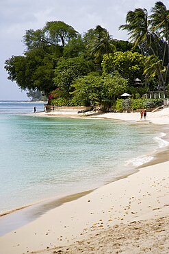 WEST INDIES Barbados St Peter People walking along beach at Gibbes Bay past one of the exclusive houses