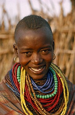 UGANDA  Karamoja District Portrait of Karamojong woman wearing multiple coloured bead necklaces.  Her hair style indicates her clan.  Colored