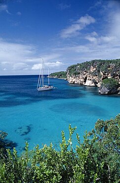 ANGUILLA  Landscape A yacht sailing on turquoise sea near vegetation covered cliffs