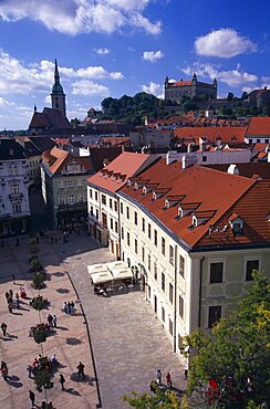 SLOVAKIA  Bratislava View over paved square and cafe  across red tiled rooftops of the Old Town towards Cathedral of St Martin and Bratislava Castle.