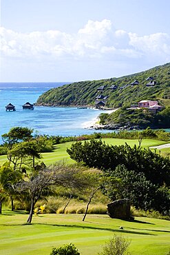 Raffles Resort Trump International Golf Course designed by Jim Fazio, The 7th fairway and 6th green with the pink Villa Juliet and Amrita Spa beyond on Godahl beach, Canouan, St Vincent & The Grenadines