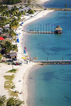 The coconut palm tree lined beach at Sandals Grande St Lucian Spa and Beach Resort hotel with tourists walking swimming or sunbathing, Gros Islet, St Lucia