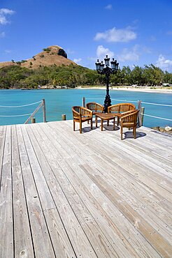 Signal Hill on Pigeon Island National Historic Park seen from a nearby wooden jetty with a table and chairs beside a wrought iron lamppost, Gros Islet, St Lucia