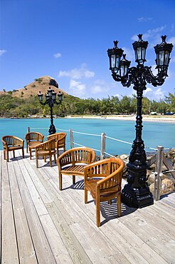 Signal Hill on Pigeon Island National Historic Park seen from a nearby wooden jetty with a table and chairs beside a wrought iron lamppost, Gros Islet, St Lucia