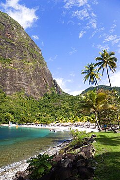 Val des Pitons The white sand beach at the Jalousie Plantation Resort Hotel with the volcanic plug of Petit Piton beyond and tourists on sunbeds beneath palapa sun shades, Soufriere, St Lucia