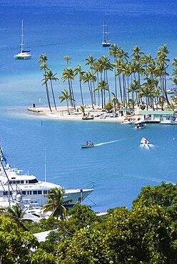 Marigot Bay Yachts at anchor beyond the small coconut palm tree lined beach of the Marigot Beach Club sitting at the entrance, Castries, St Lucia