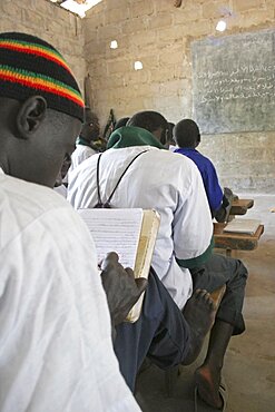 Tanji Village, Muslim boys writing in arabic at their desks while attending an islamic religious class at the Ousman Bun Afan Islamic school, Blackboard on wall in front of them, Tanji, Western Gambia, The Gambia