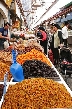 Women with baby in pram making purchase at stall selling dried fruit and nuts including sultanas apricots and peanuts in covered main food market of Jerusalem, Jerusalem, Israel