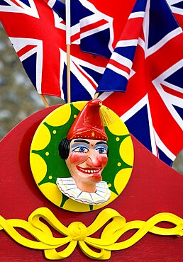 Findon village Sheep Fair Bright red Punch and Judy stand with Union Jack flags and a carved image of Punch, United Kingdom