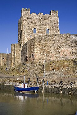 Ireland, County Antrim, Carrickfergus, Castle exterior with a boat moored in the foreground