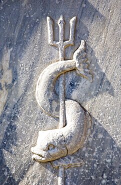 Greece, Athens, Close cropped view of stone carving of sea creature curved around trident