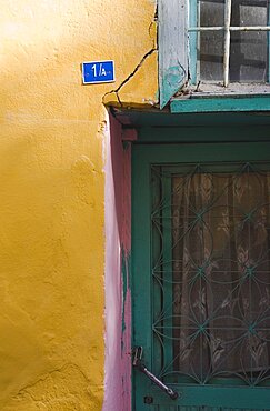 Turkey, Aydin Province, Kusadasi, Detail of exterior facade of house in the old town numbered 1A With yellow and pink painted walls and turquoise painted door and window frames