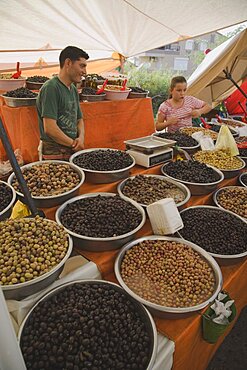 Turkey, Aydin Province, Kusadasi, Stall at weekly market selling olives and nuts with male stall holder and young girl standing behind display and set of electronic scales