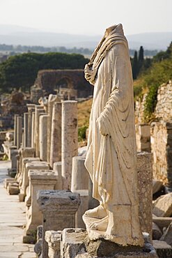 Turkey, Izmir Province, Selcuk, Ephesus, Headless statue on plinth in line of ruined pillars and empty pedestals in antique city of Ephesus on the Aegean sea coast