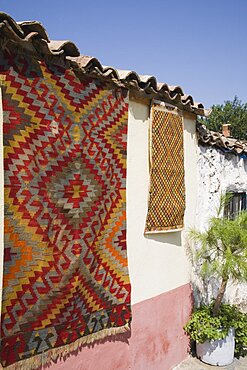 Turkey, Izmir Province, Selcuk, Kilim hanging up to dry in sun from wall of village house